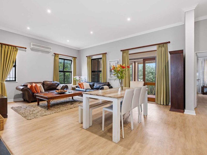 Spacious open-plan living and dining area featuring light laminate flooring, recessed downlighting, and direct access to the outdoor patio through sliding glass doors.