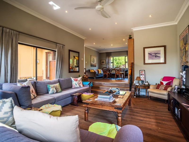 Spacious open-plan living and dining area featuring laminate flooring, recessed lighting, a ceiling fan, and sliding doors leading to an outdoor patio.