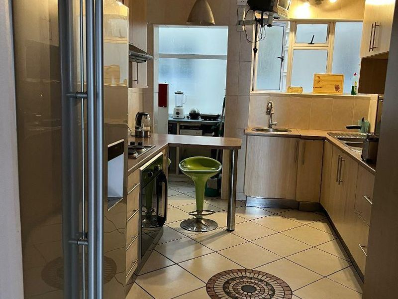 A functional kitchen featuring light wood-tone cabinetry, tiled flooring with a decorative inlay, and integrated appliances, offering a practical layout for daily use.