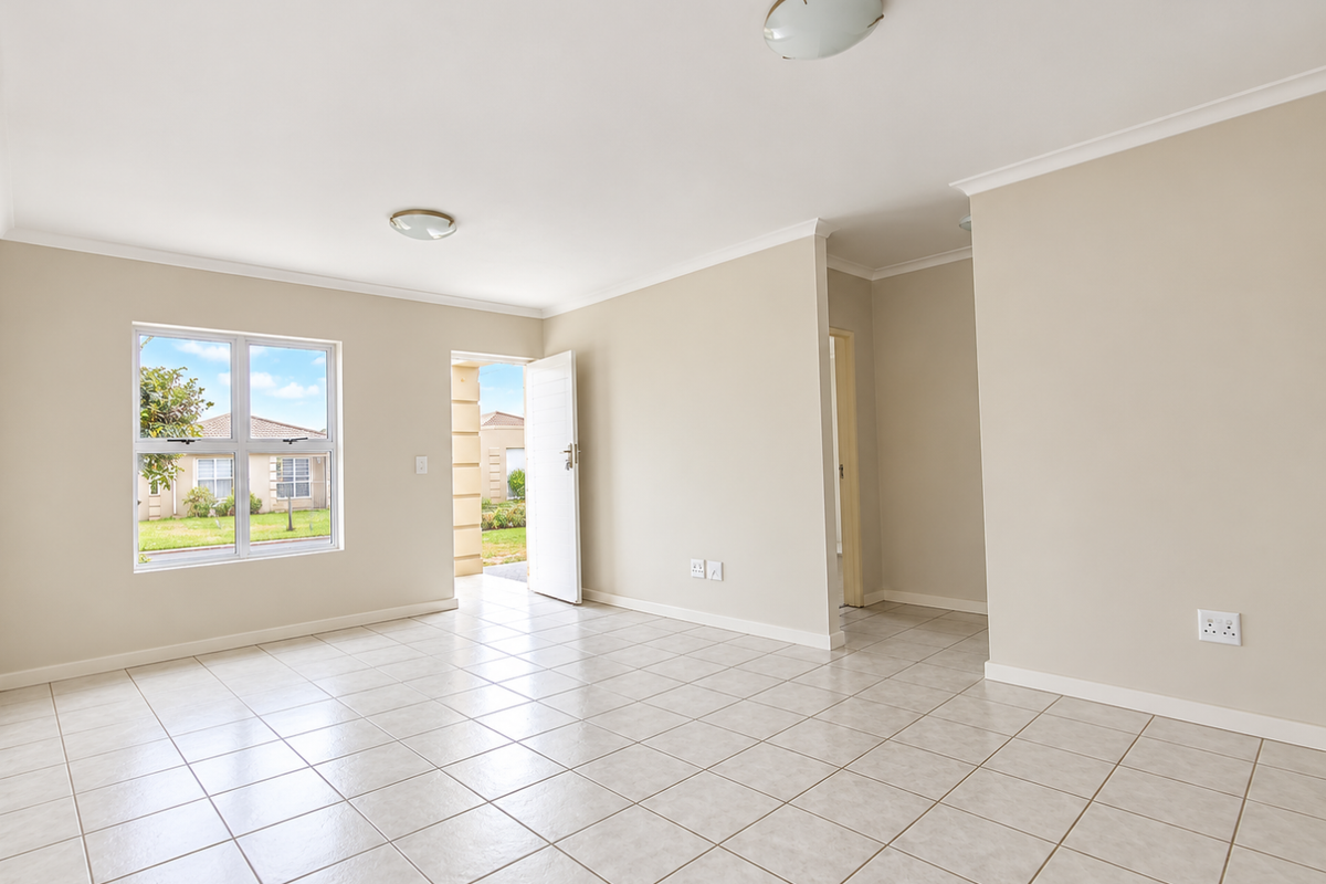 A bright, empty living area featuring neutral tiled flooring, coved ceilings, and direct access to the exterior through a glass-paneled door.