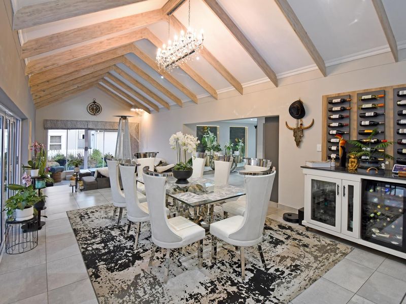 Spacious dining area featuring a vaulted ceiling with exposed timber beams, built-in wine storage, and large bi-fold doors opening to the exterior.