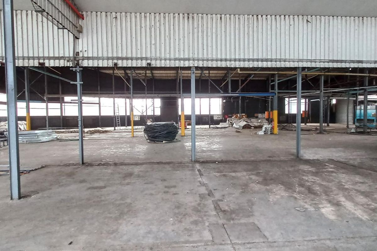 Large open-plan industrial warehouse space featuring high ceilings, exposed steel structural columns, and durable concrete flooring, suitable for various commercial or manufacturing operations.