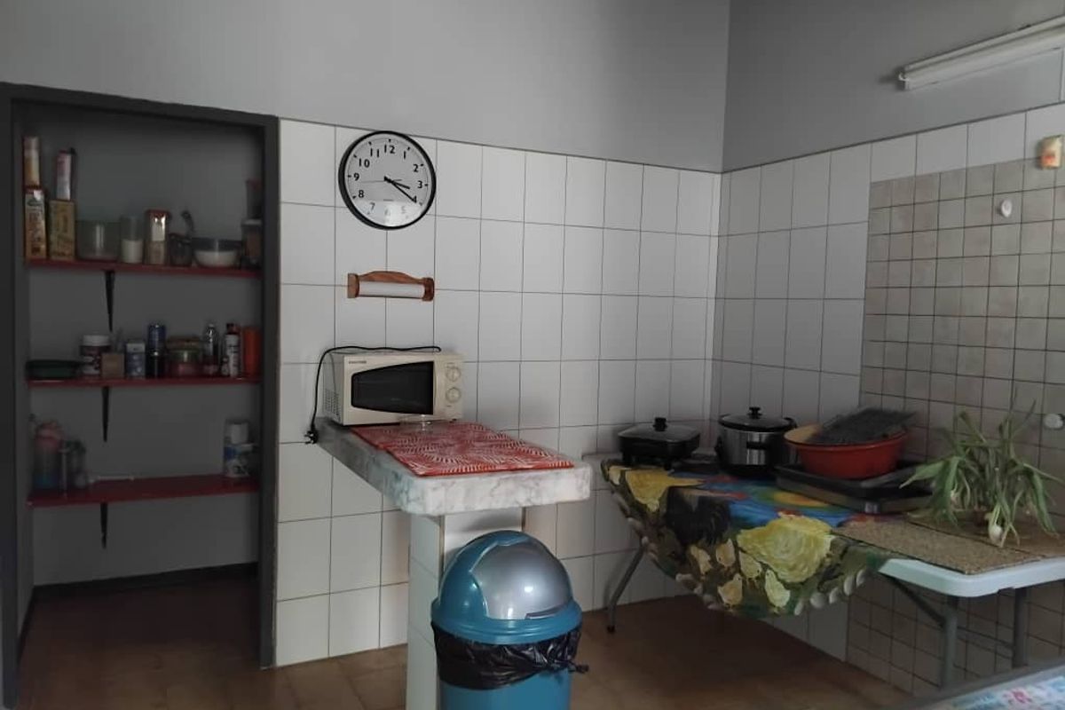 A functional kitchen area featuring tiled walls, a built-in prep counter, and an adjacent walk-in pantry space.