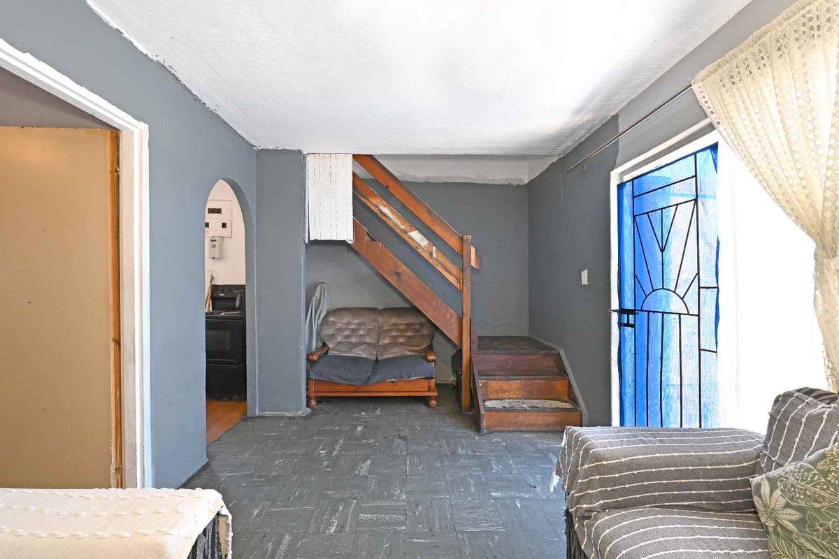 Living area featuring a wooden staircase, tiled flooring, and an arched entryway leading to an adjacent room.