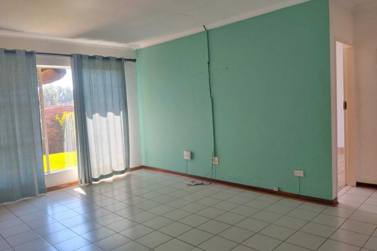 An empty living room featuring tiled flooring, a sliding glass door providing natural light, and visible wall-mounted electrical wiring.