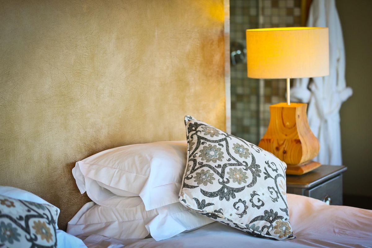 Close-up view of a bedroom interior featuring a textured feature wall and integrated lighting, with a glimpse of an adjacent bathroom area.