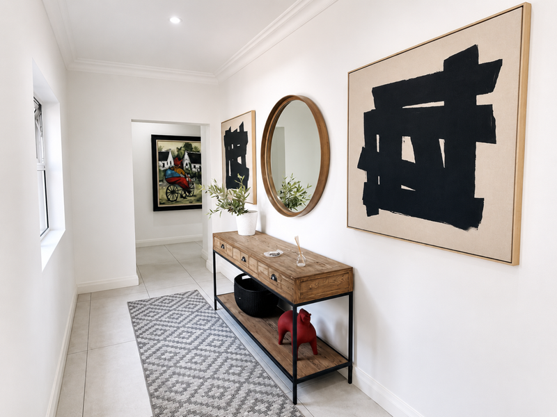 A bright and well-maintained hallway featuring neutral tiled flooring, recessed downlighting, and clean architectural lines.