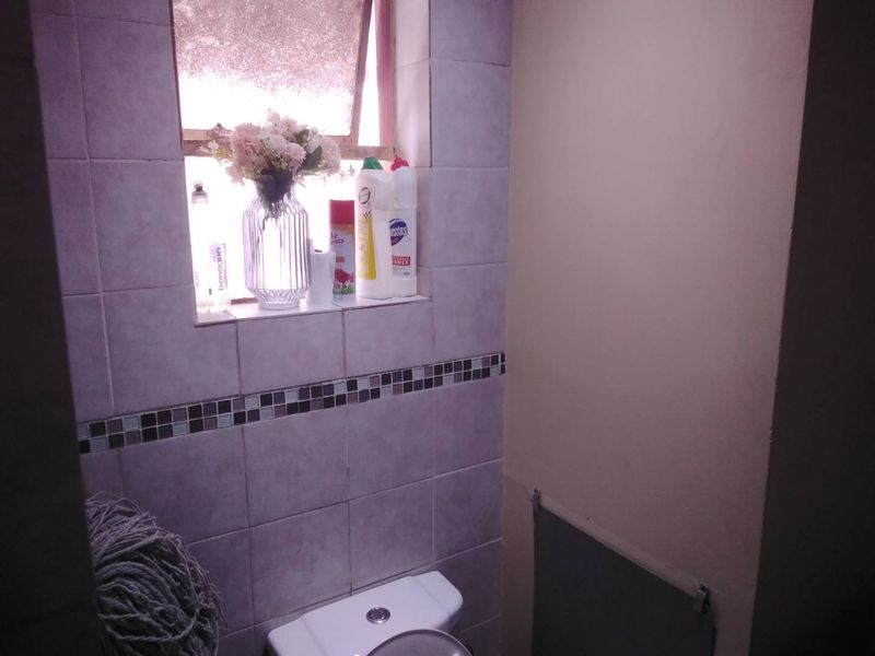A compact bathroom featuring tiled walls with a decorative mosaic border and a standard top-flush toilet.