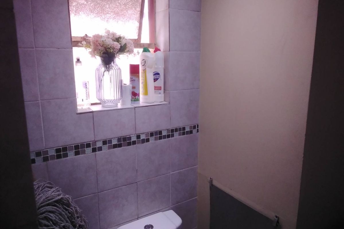 A compact bathroom featuring tiled walls with a decorative mosaic border and a standard top-flush toilet.