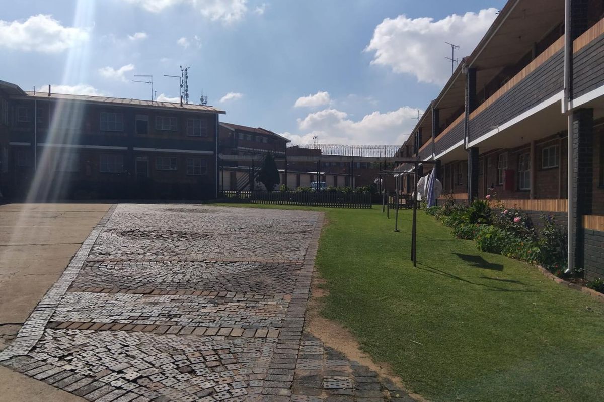 A view of the apartment complex courtyard featuring a brick-paved driveway, a well-maintained lawn, and multi-story brick building facades.