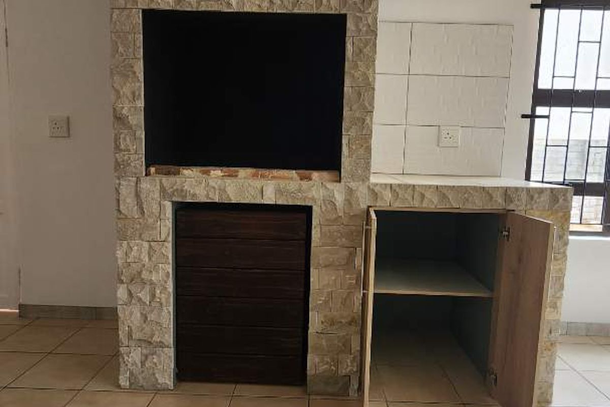 Indoor built-in braai area featuring stone cladding, tiled flooring, and integrated storage cabinetry.