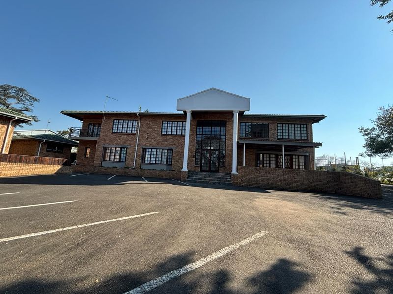 Front exterior view of a two-story brick office building featuring a paved parking area, covered entrance with columns, and multiple windows.