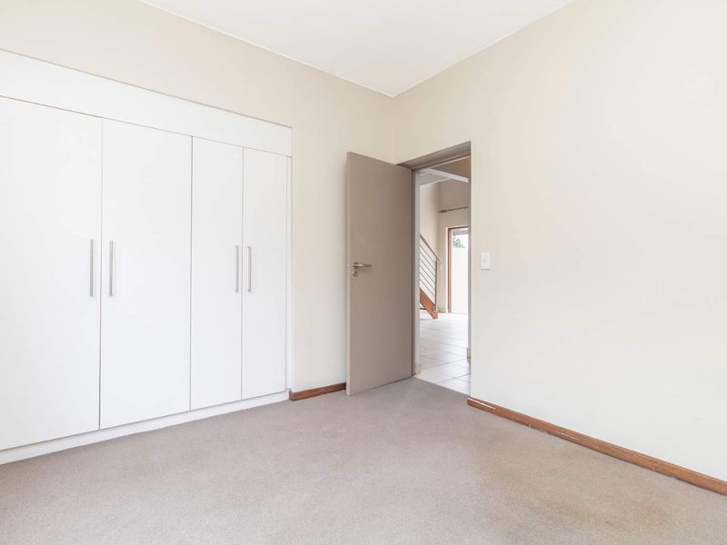 A bright, empty bedroom featuring built-in white cabinetry and neutral wall finishes, providing a clean canvas for personalization.
