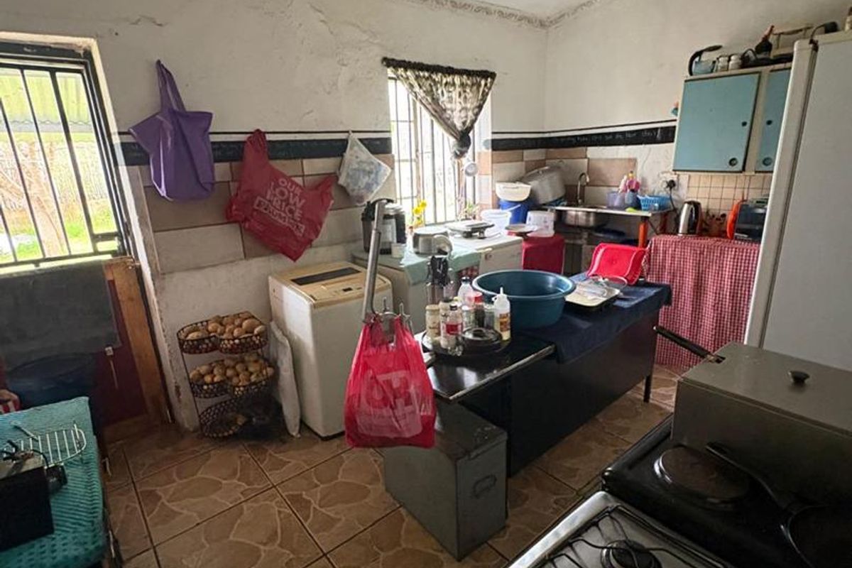 A dated kitchen featuring tiled flooring, basic cabinetry, and a gas stove, requiring significant renovation and cosmetic updates to improve functionality and aesthetic appeal.