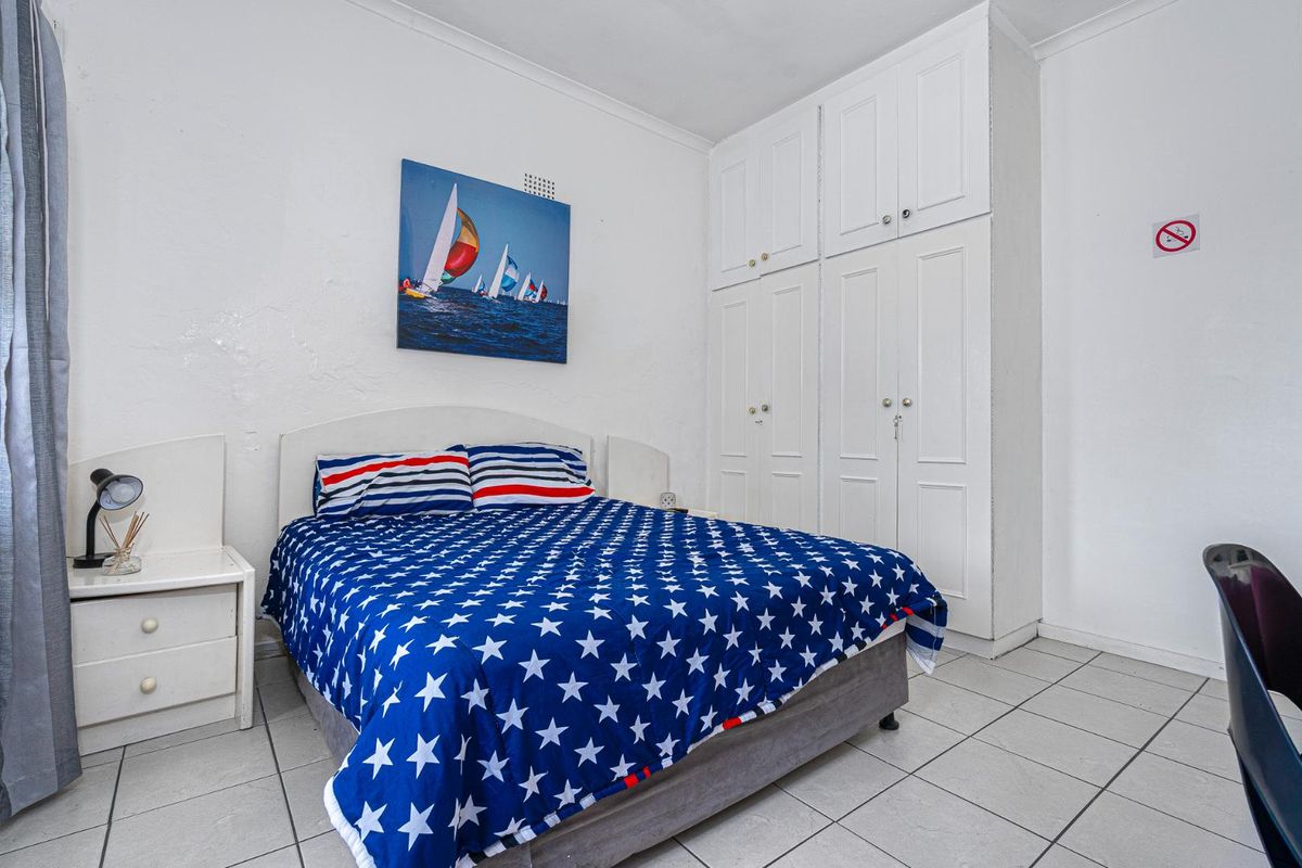 A bedroom featuring built-in floor-to-ceiling cabinetry and tiled flooring.