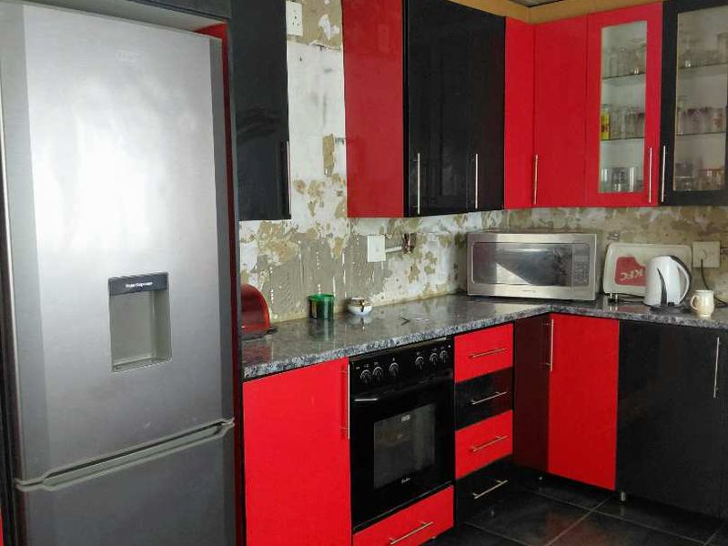 Kitchen featuring red and black cabinetry, built-in oven, and tiled flooring. The wall area requires finishing or backsplash installation to complete the space.