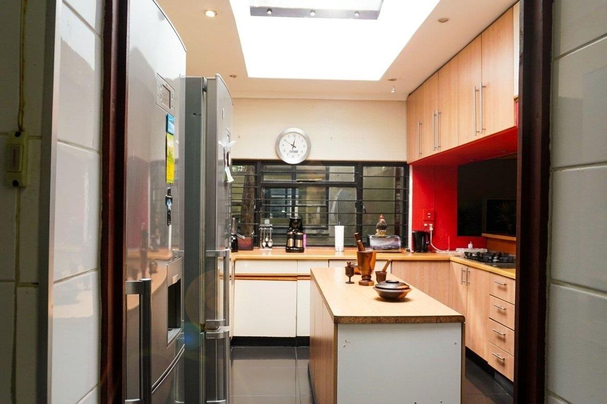 A functional kitchen featuring a central island, built-in cabinetry, integrated hob, and a large skylight providing ample natural light.