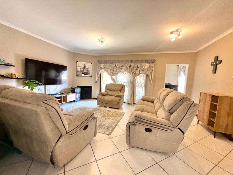 Spacious living room featuring tiled flooring, a built-in fireplace, and sliding glass doors with security gates leading to the exterior.
