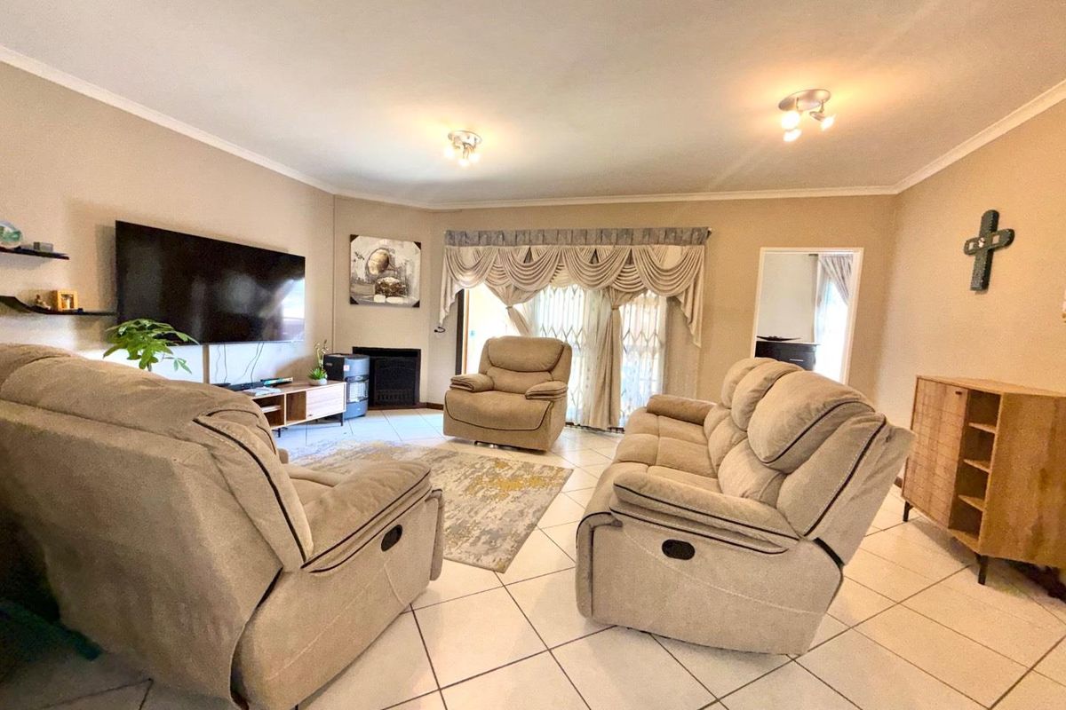 Spacious living room featuring tiled flooring, a built-in fireplace, and sliding glass doors with security gates leading to the exterior.