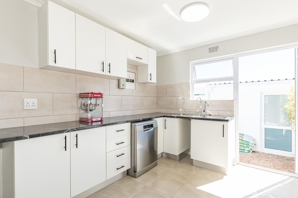 Modern kitchen featuring white cabinetry, stone-look countertops, tiled backsplash, and direct access to an outdoor area.