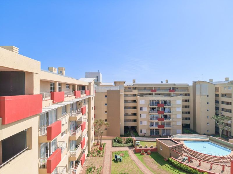 Elevated view of a townhouse complex featuring a communal swimming pool, landscaped garden areas, and multiple residential blocks with private balconies.