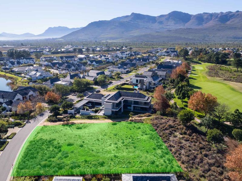 Aerial view of a vacant residential plot situated within a scenic estate, featuring golf course frontage and mountain views.