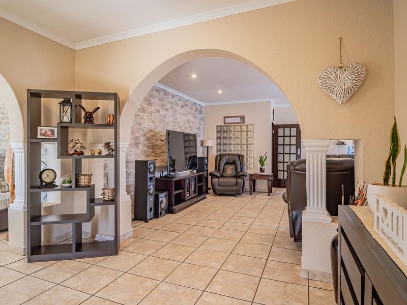 Spacious living area featuring arched architectural details, stone veneer accent walls, and neutral ceramic floor tiling throughout the open-plan layout.