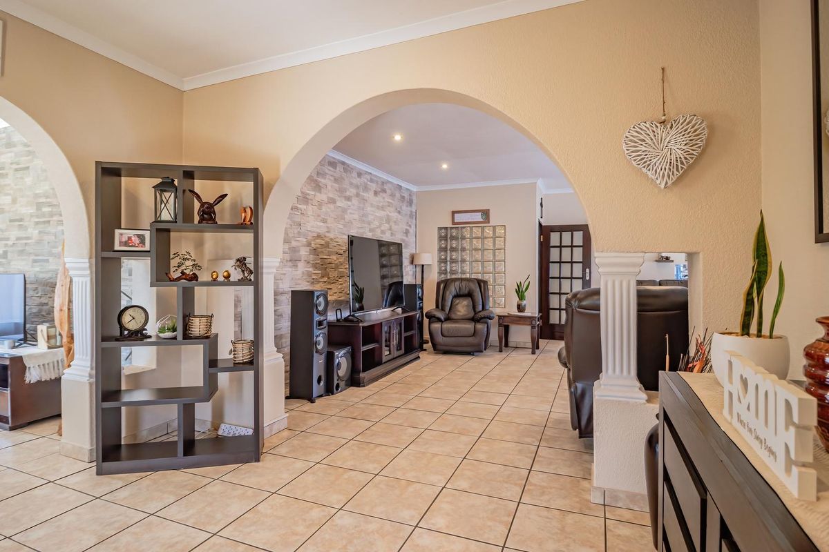 Spacious living area featuring arched architectural details, stone veneer accent walls, and neutral ceramic floor tiling throughout the open-plan layout.