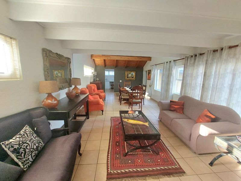 Spacious open-plan living and dining area featuring exposed timber ceiling beams and neutral ceramic floor tiles throughout.