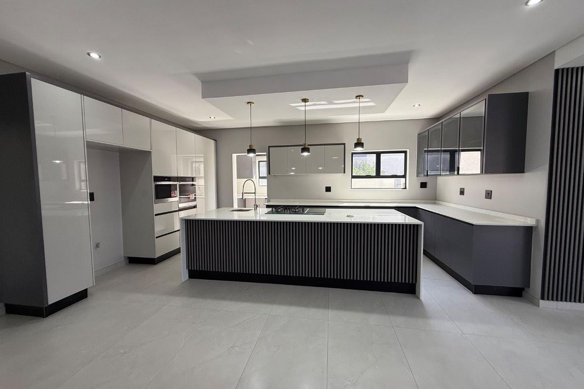 Modern kitchen featuring a large central island with a built-in gas hob, sleek cabinetry, integrated appliances, and recessed ceiling lighting.