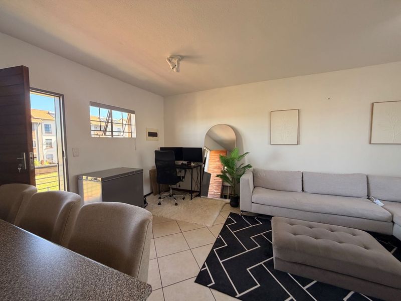 Open-plan living area featuring tiled flooring, a sliding door providing natural light, and a neutral layout suitable for versatile furniture arrangements.