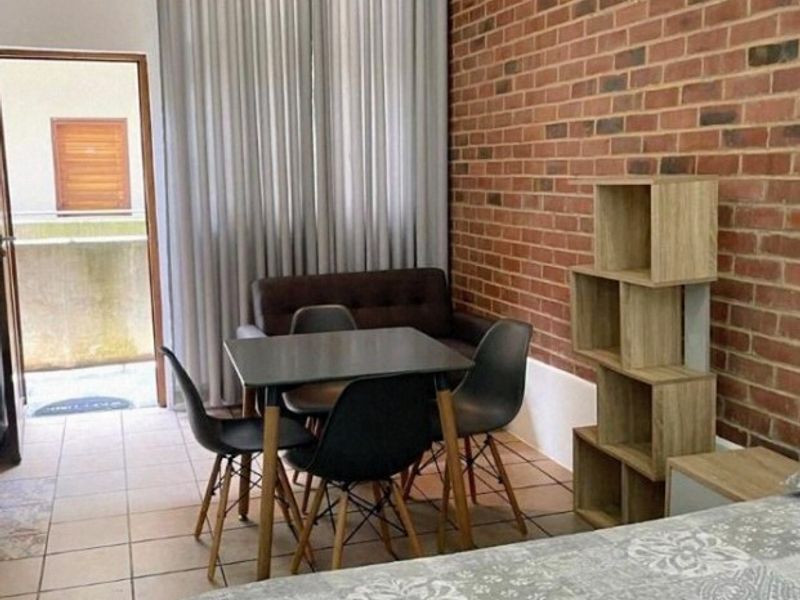 Bedroom featuring an exposed brick wall, tiled flooring, and direct access to a private balcony through a doorway.