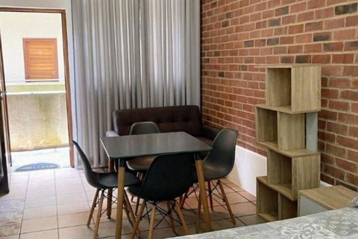 Bedroom featuring an exposed brick wall, tiled flooring, and direct access to a private balcony through a doorway.