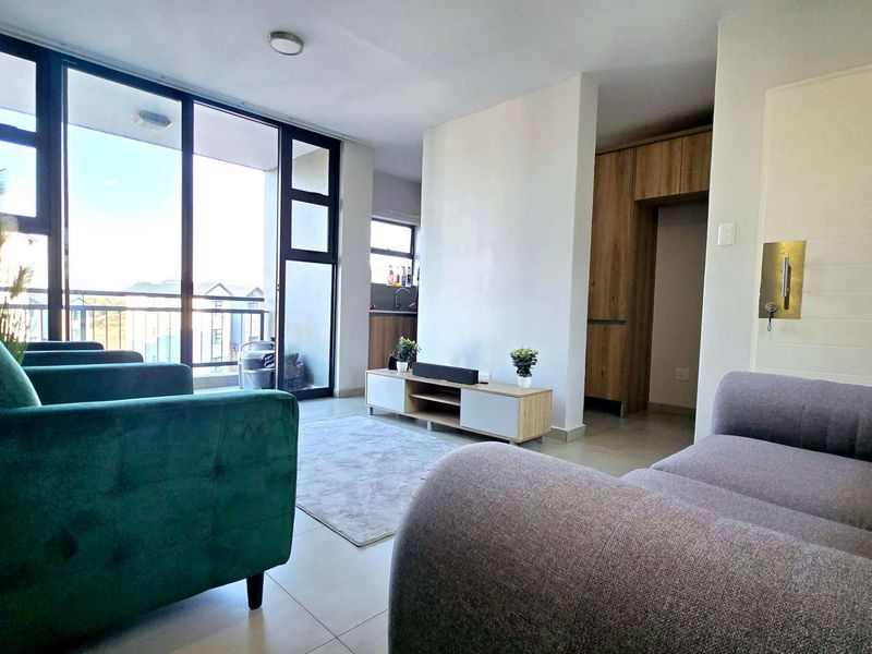 Open plan living area featuring tiled floors, built-in cabinetry, and large sliding glass doors leading to a balcony, providing ample natural light.