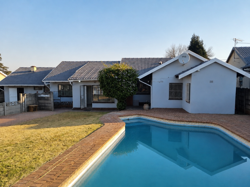 Rear view of the house featuring a swimming pool, brick paved patio area, and a well-maintained tiled roof structure.