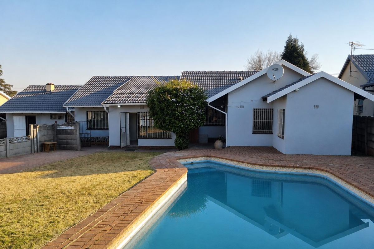 Rear view of the house featuring a swimming pool, brick paved patio area, and a well-maintained tiled roof structure.