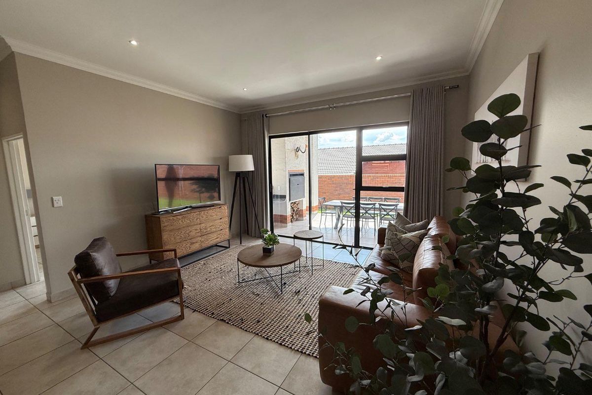 A well-maintained living room featuring large sliding glass doors that open onto a covered patio area, providing seamless indoor-outdoor flow.