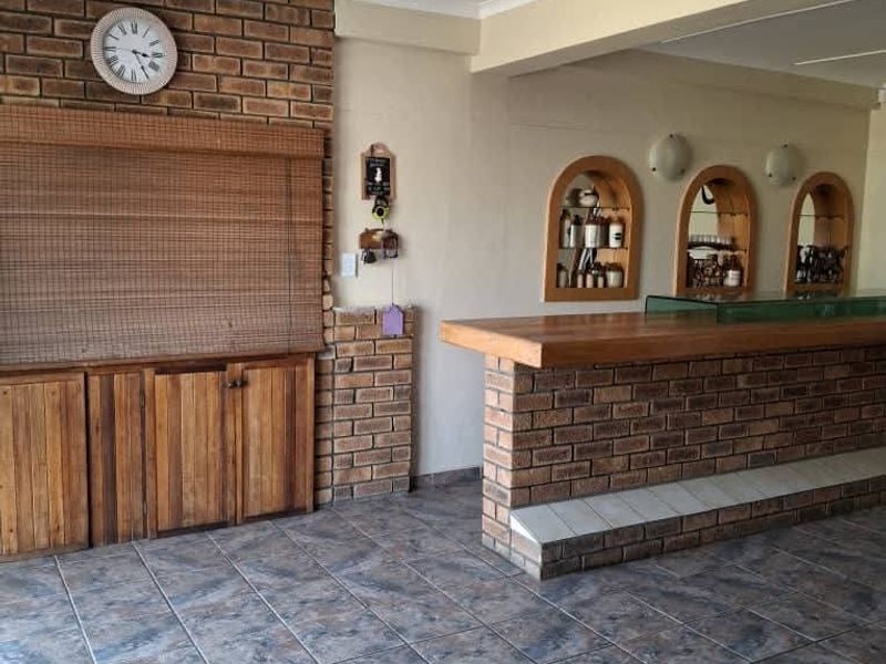 A dedicated bar area featuring a built-in brick counter, arched wall niches for display, and durable tiled flooring.
