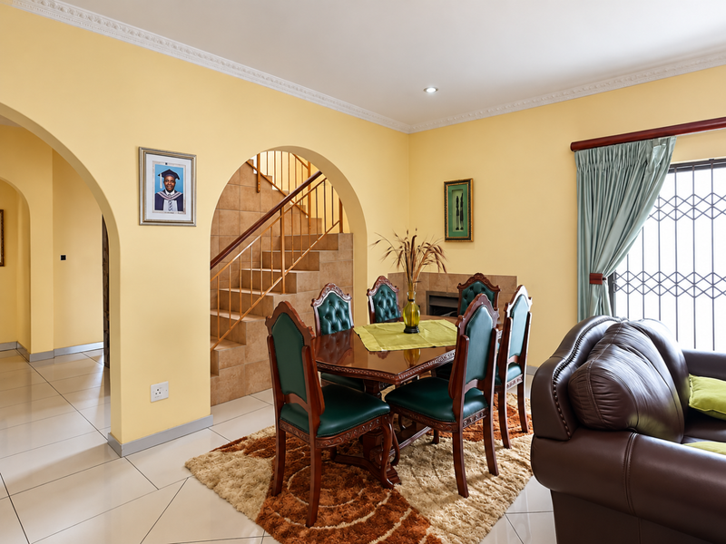 Dining area featuring tiled flooring, crown molding, and an arched opening leading to a tiled staircase with a metal balustrade.