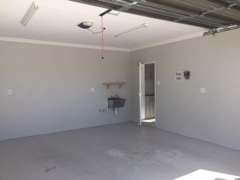 A clean, empty double garage featuring concrete flooring, a utility sink, and an integrated electrical distribution board.