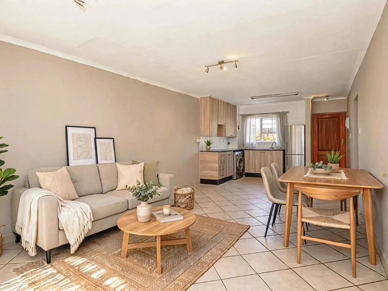 Open-plan living and dining area featuring tiled floors and a functional kitchen with built-in cabinetry and modern finishes.