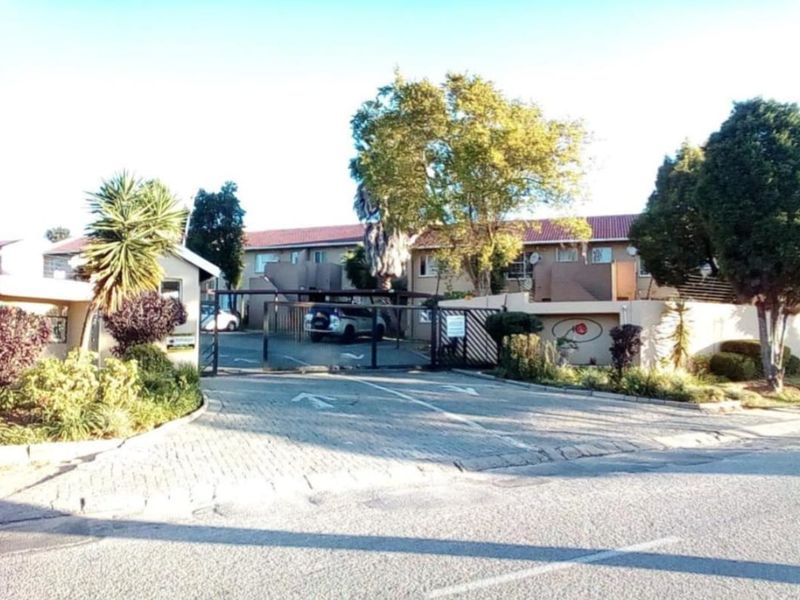 Front view of the apartment complex entrance featuring a secure gated access point, paved driveway, and established landscaping.