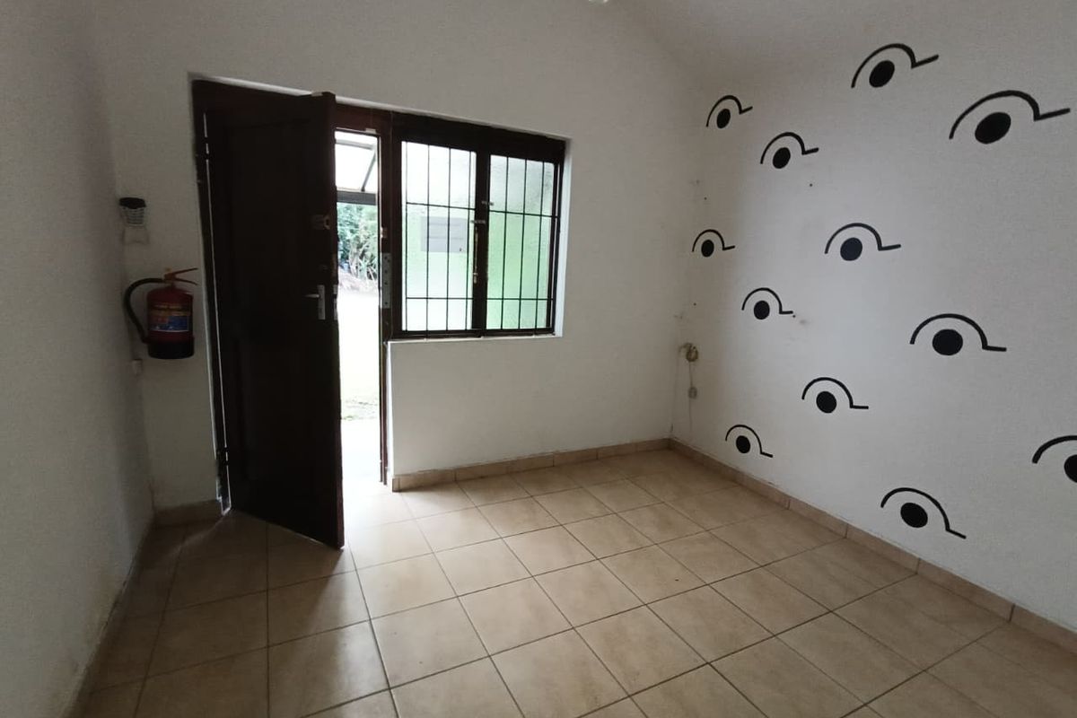 An empty room featuring tiled flooring, a security gate, and window burglar bars. The space is ready for renovation or staging.