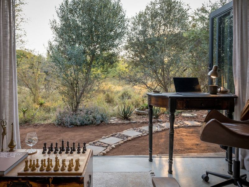 A bright home office space featuring large glass sliding doors that open directly onto a natural garden setting.