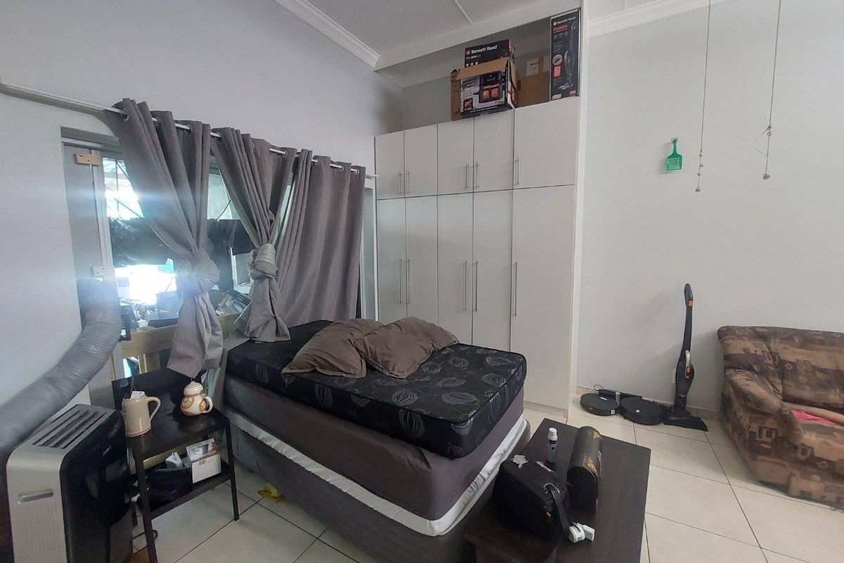 A bedroom featuring built-in floor-to-ceiling white cabinetry and tiled flooring.