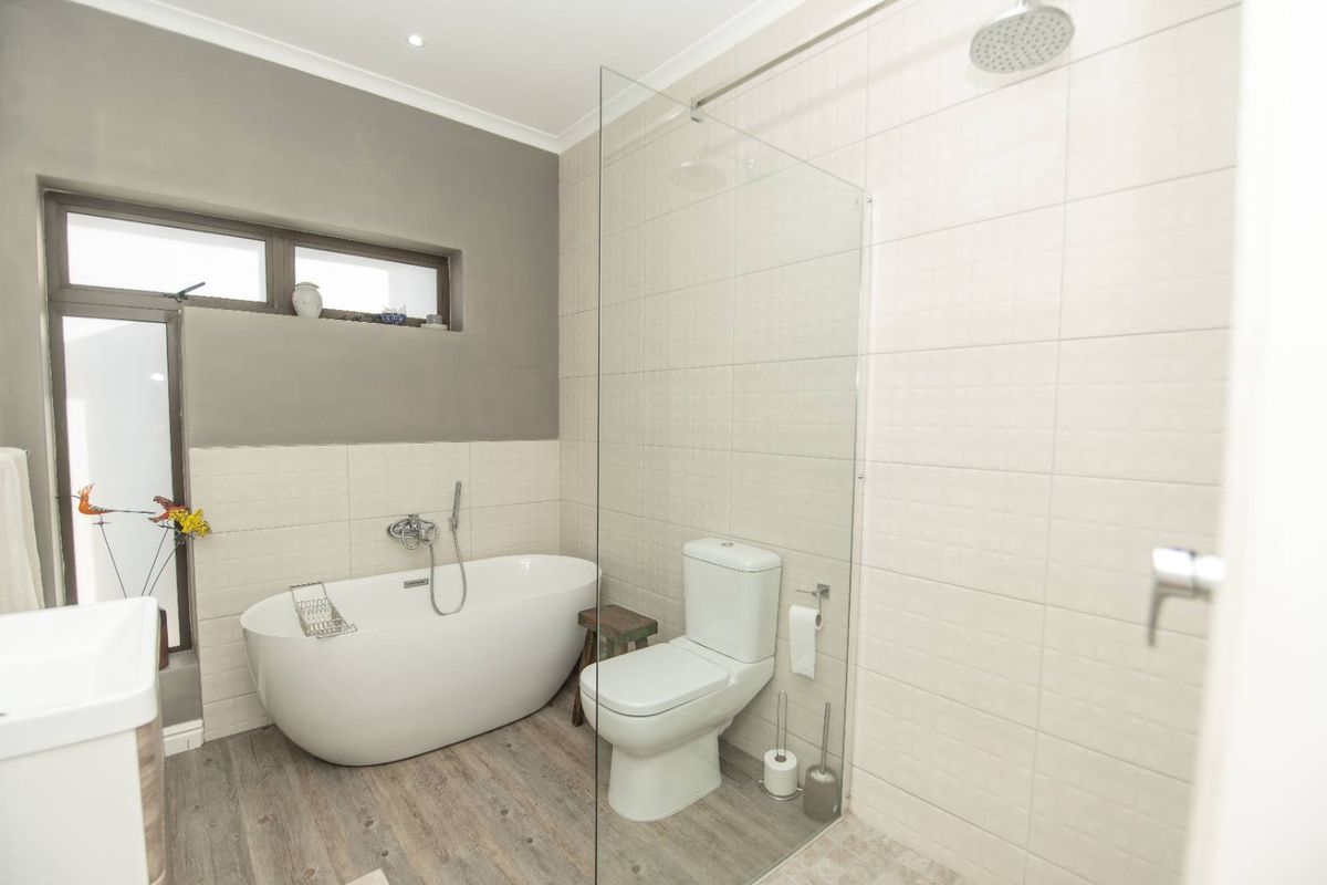 Modern bathroom featuring a freestanding bathtub, glass-enclosed walk-in shower, contemporary fixtures, and neutral tiled finishes.