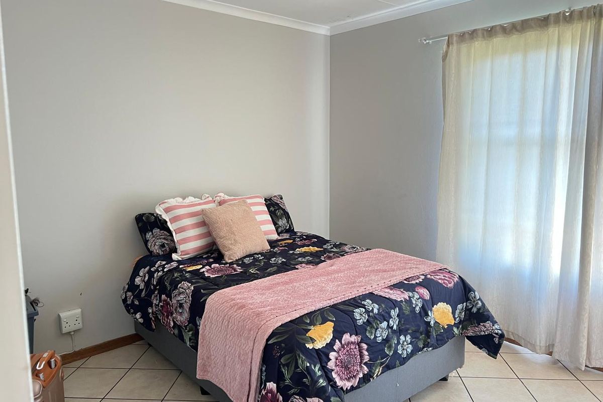 A functional bedroom featuring neutral wall paint, tiled flooring, and coved ceiling details, providing a clean and simple living space.