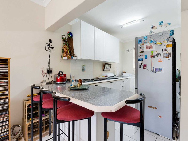 A functional kitchen featuring white cabinetry, a breakfast bar with laminate countertops, and tiled flooring, offering a practical layout for daily use.