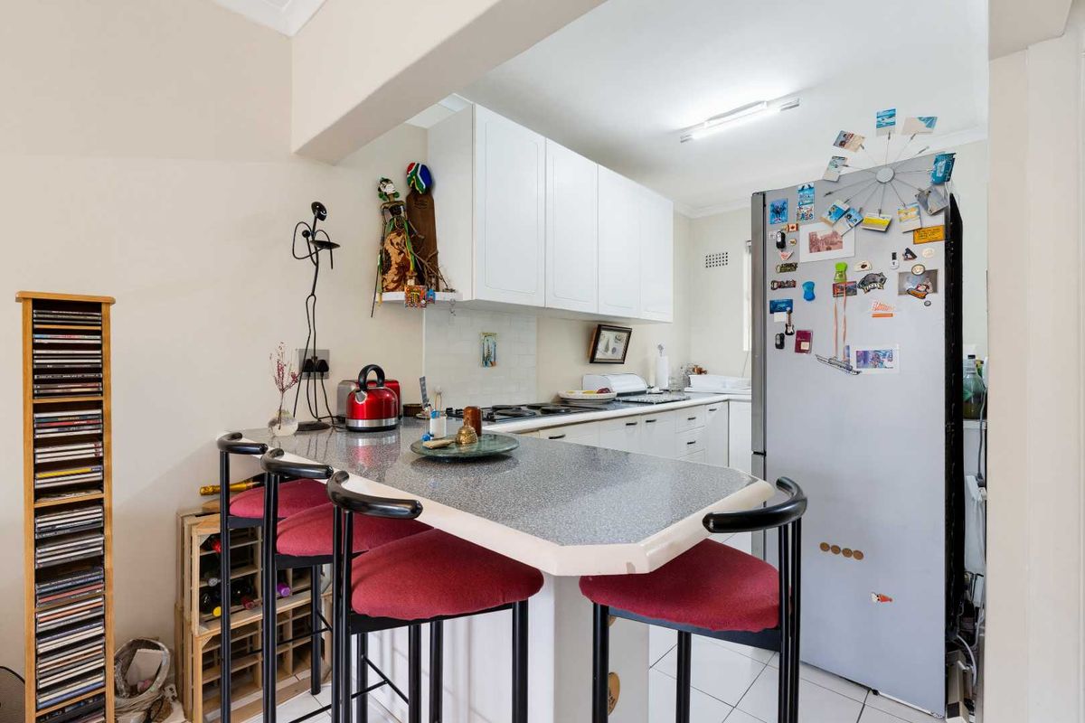 A functional kitchen featuring white cabinetry, a breakfast bar with laminate countertops, and tiled flooring, offering a practical layout for daily use.