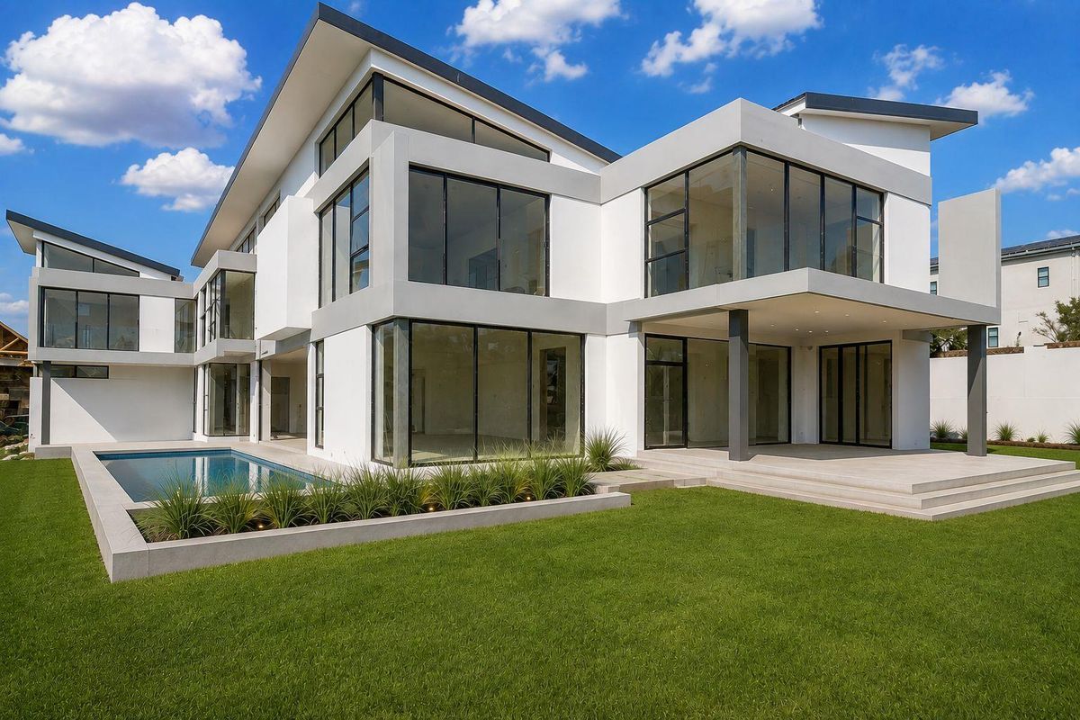 A modern luxury residence featuring a sleek architectural design, expansive glass windows, a private swimming pool, and a well-maintained rear garden.
